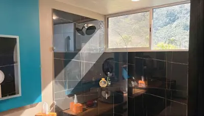 a bathroom with a shower with a sink and a mirror at Mei Tai Cacao Lodge in Bijagua