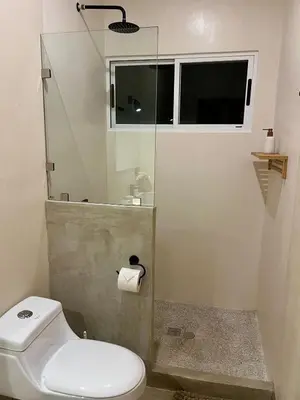 a bathroom with a toilet and a glass shower at Teva Guest House with Shared pool in Cabuya