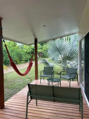 a porch with two chairs and a hammock on it at Teva Guest House with Shared pool in Cabuya