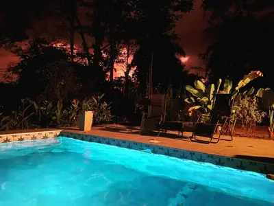 a swimming pool at night with two chairs and a table at Private Cabina at Yoga Center in Ojochal