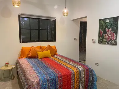 a bedroom with a bed with orange pillows and a window at Private Cabina at Yoga Center in Ojochal