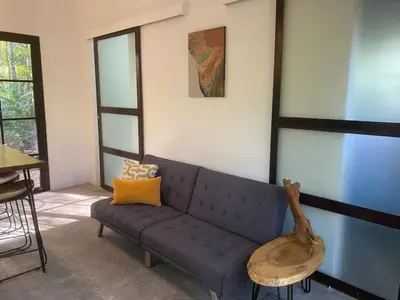 a living room with a blue couch and a table at Private Cabina at Yoga Center in Ojochal