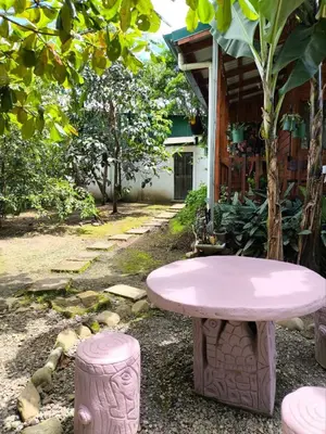 a pink table and two stools in a garden at Cabin in Orosi in Orosí