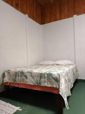 a bed in a room with a white wall at Cabin in Orosi in Orosí