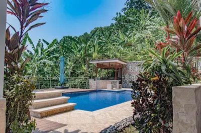 a swimming pool in a garden with plants at Villa Azulita in Tarcoles