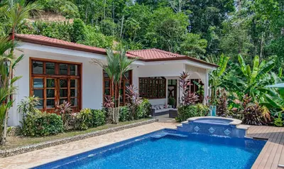 a villa with a swimming pool in front of a house at Villa Azulita in Tarcoles
