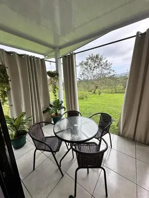 a patio with a table and chairs on a porch at Casa Vista Arenal in Fortuna