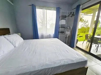 a bedroom with a large white bed and a balcony at Casa Vista Arenal in Fortuna