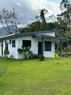 a white house with a green lawn in front of it at Casa Vista Arenal in Fortuna