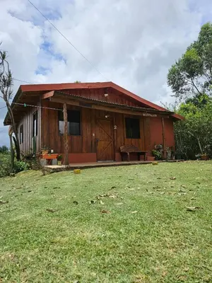a small house with a grass yard in front of it at Ecos del Poás vista al jardín in Dulce Nombre
