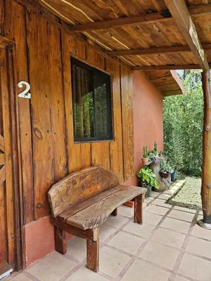a wooden building with a bench on a patio at Ecos del Poás vista al jardín in Dulce Nombre