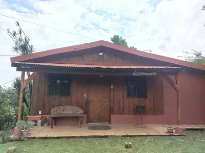 a small red house with a bench in front of it at Ecos del Poás vista al jardín in Dulce Nombre