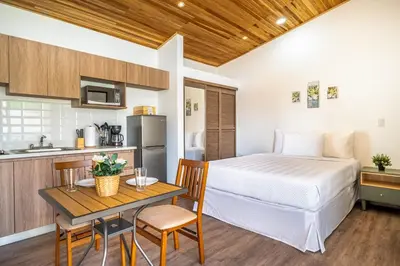 a bedroom with a bed and a table and a kitchen at Macondo Ecolodge Apt 4 - Estrella de Fuego in Coco
