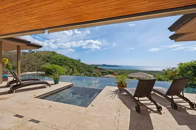 a patio with two chairs and a swimming pool at Serene Oceanview Villa with Pool in Playa Flamingo
