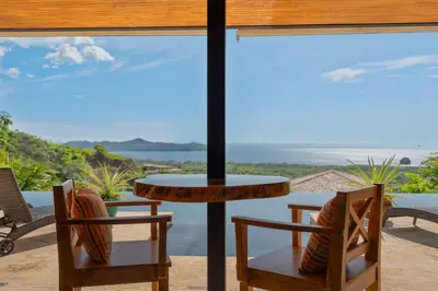 a table and chairs on a balcony with a view at Serene Oceanview Villa with Pool in Playa Flamingo