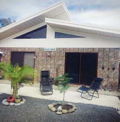 a house with two chairs and palm trees in front of it at Ecohacienda Perla Marina in Sardinal