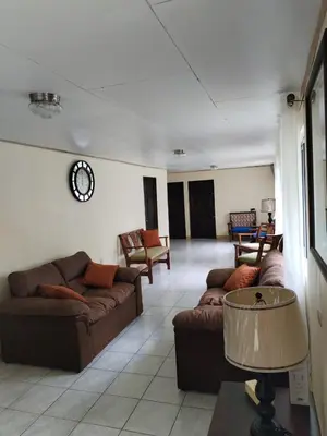 a living room with couches and a clock on the wall at Mini reserva La Naciente Mi casa es tu casa in Tapantí