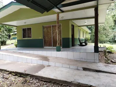 a front porch of a house with a green at Mini reserva La Naciente Mi casa es tu casa in Tapantí
