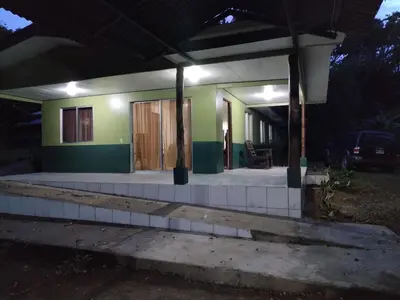 a small house with a porch at night at Mini reserva La Naciente Mi casa es tu casa in Tapantí