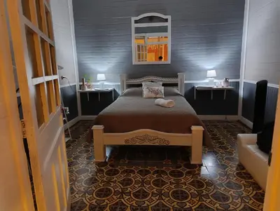 a bedroom with a bed with two tables and a mirror at Vintage and Colonial House - 7min from Airport in Alajuela City