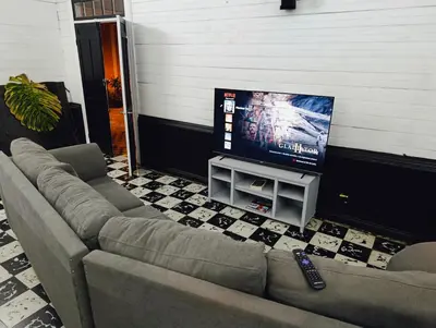 a living room with a couch and a flat screen tv at Vintage and Colonial House - 7min from Airport in Alajuela City