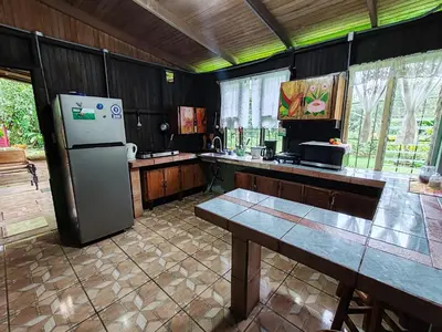 a kitchen with a refrigerator and a table in it at Casa La Esperanza in Chachagua