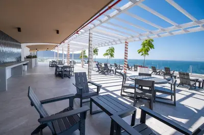 a patio with tables and chairs and a view of the ocean at Stylish 1-BR Oceanfront Condo with Panoramic Views in Jacó