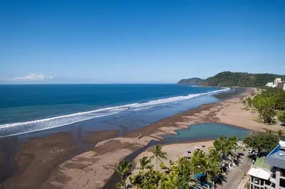an aerial view of a beach with palm trees and the ocean at Stylish 1-BR Oceanfront Condo with Panoramic Views in Jacó