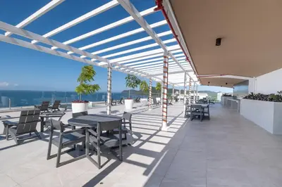 a patio with tables and chairs on a roof at Stylish 1-BR Oceanfront Condo with Panoramic Views in Jacó