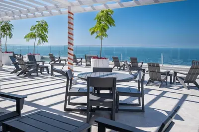 a patio with tables and chairs and the ocean at Stylish 1-BR Oceanfront Condo with Panoramic Views in Jacó
