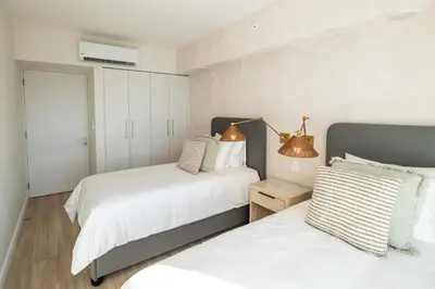 a bedroom with two beds and a table with a lamp at Stylish 2-BR Oceanfront Condo with Panoramic Views in Jacó