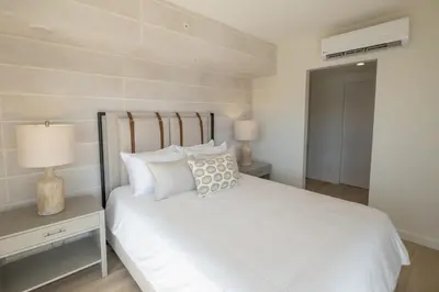 a bedroom with a white bed and a nightstand with a lamp at Stylish 2-BR Oceanfront Condo with Panoramic Views in Jacó