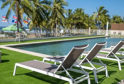 a group of lawn chairs next to a swimming pool at Stylish 2-BR Oceanfront Condo with Panoramic Views in Jacó