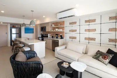 a living room with a couch and a kitchen at Stylish 2-BR Oceanfront Condo with Panoramic Views in Jacó