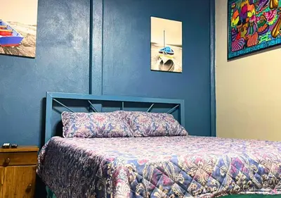 a blue bedroom with a bed and paintings on the wall at Peace of the forest in Llano Grande