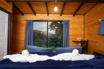 a bedroom with a bed and a large window at Hotel de Montaña Gema del Bosque in El Copey