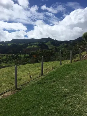 a fence in a field with mountains in the background at Modern Mediterranean Santorini House in Cartago