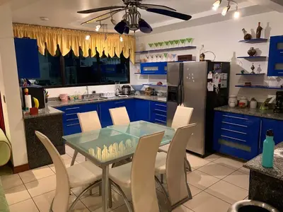 a kitchen with blue cabinets and a glass table and chairs at Modern Mediterranean Santorini House in Cartago