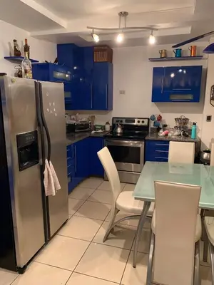 a kitchen with blue cabinets and a table and a refrigerator at Modern Mediterranean Santorini House in Cartago