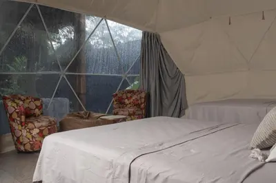 a bedroom with a tent with two beds and chairs at Bambuk Bio Dome Uvita beach front in Uvita