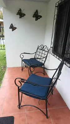 two chairs on a porch with butterflies on the wall at Casita Thisa Chibú in Bijagua