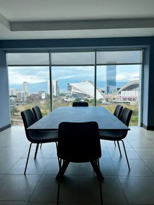 a table and chairs in a room with a large window at Apartment in La Sabana in San José