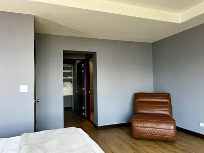 a bedroom with a bed and a leather chair at Apartment in La Sabana in San José