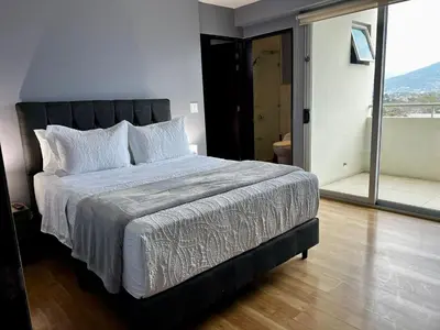 a bedroom with a large bed with a large window at Apartment in La Sabana in San José