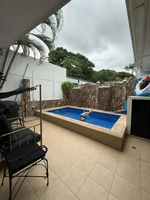 a swimming pool in a yard with a chair next to it at Casa residencial en playa Herradura in Herradura