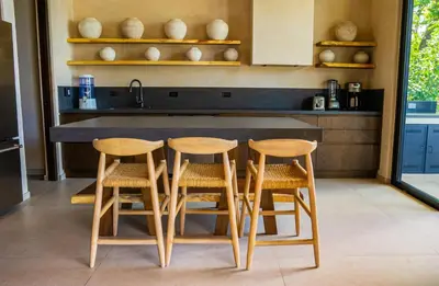 a kitchen with a counter with four chairs around it at Casa Lagom, Luxurious Oasis with Infinity Pool! in La Cruz