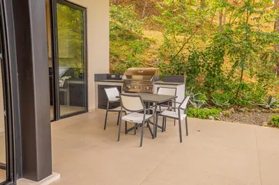 a patio with a table and chairs and a kitchen at Casa Lagom, Luxurious Oasis with Infinity Pool! in La Cruz