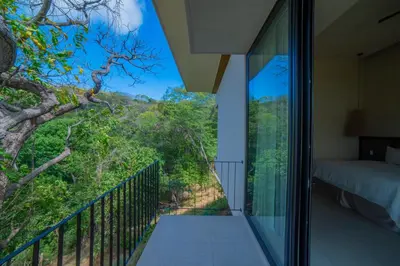 a bedroom with a balcony with a view of the forest at Casa Lagom, Luxurious Oasis with Infinity Pool! in La Cruz