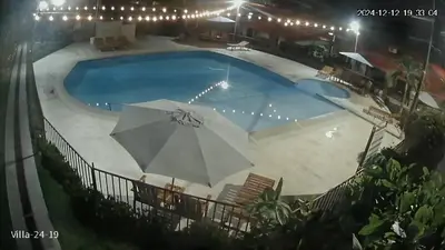 a pool at night with an umbrella and chairs at Villas jaco costa rica in Jacó