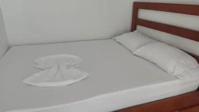 a white bed with a wooden headboard and white pillow at Villas jaco costa rica in Jacó